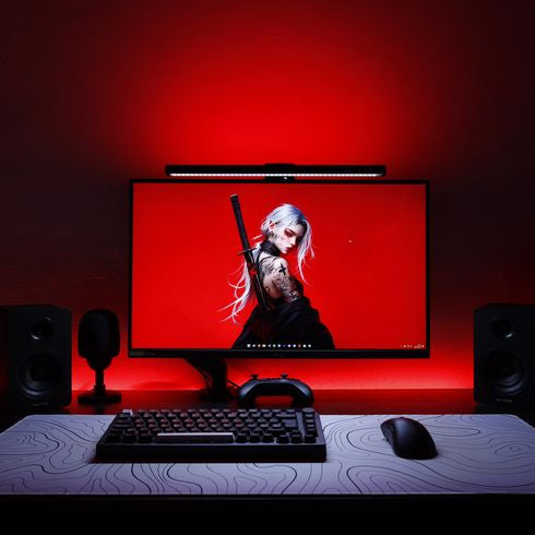 Gaming setup with monitor, keyboard, and mouse on a desk under red lighting