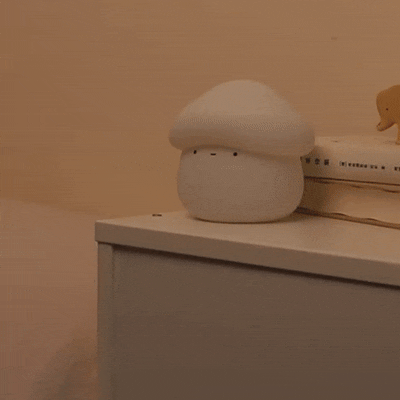 Soft warm mushroom lamp being turned on in a cozy bedroom setup for aesthetic lighting.