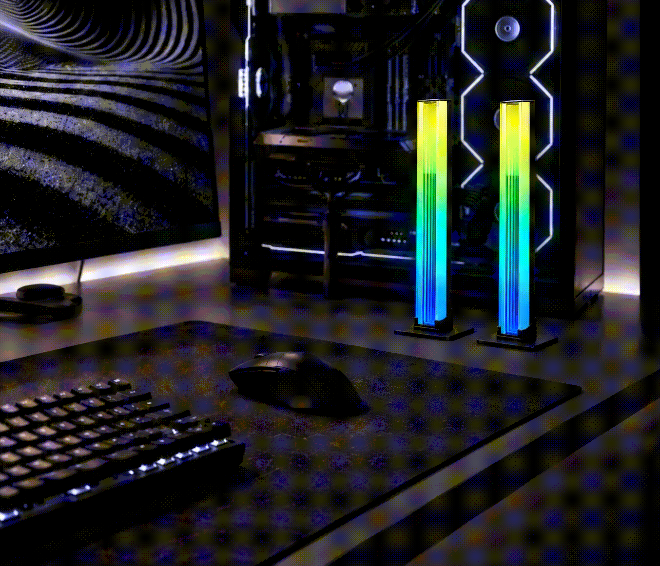 Pair of RGB gaming desk lights positioned beside a PC monitor and keyboard.