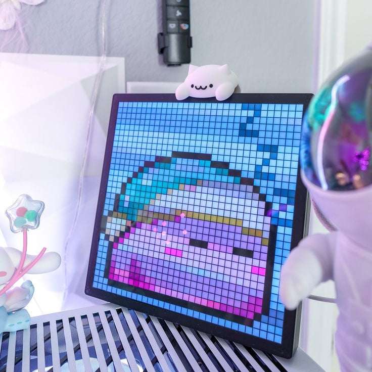 Digital art display with pixelated design of a cat in a bubble, surrounded by plush toys.